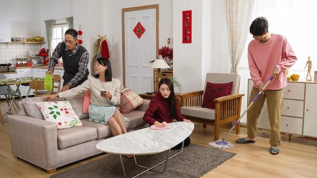 lazy-asian-mother-playing-with-phone-sofa-giving-command-with-hand-gestures-while-other-family-memeb